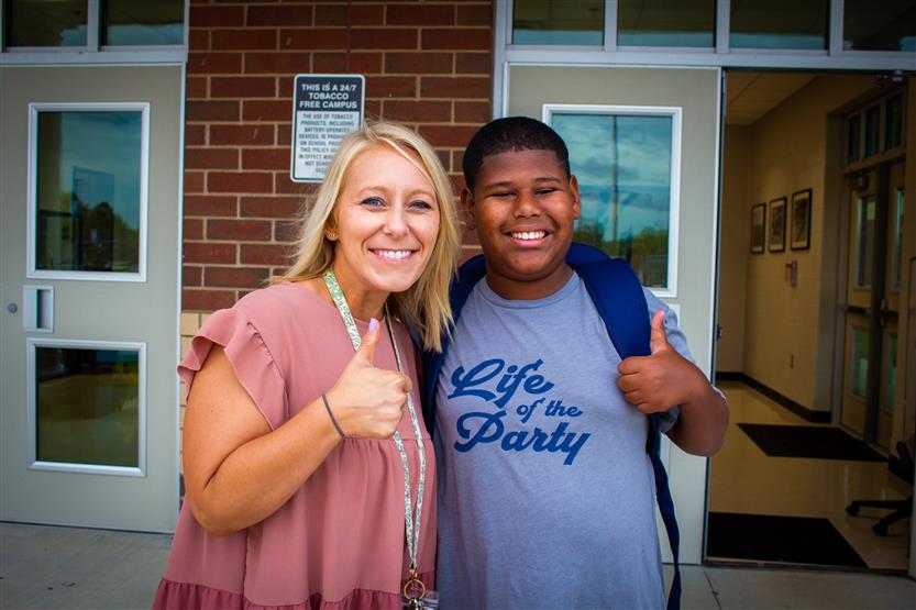 An adult and student give a thumbs up